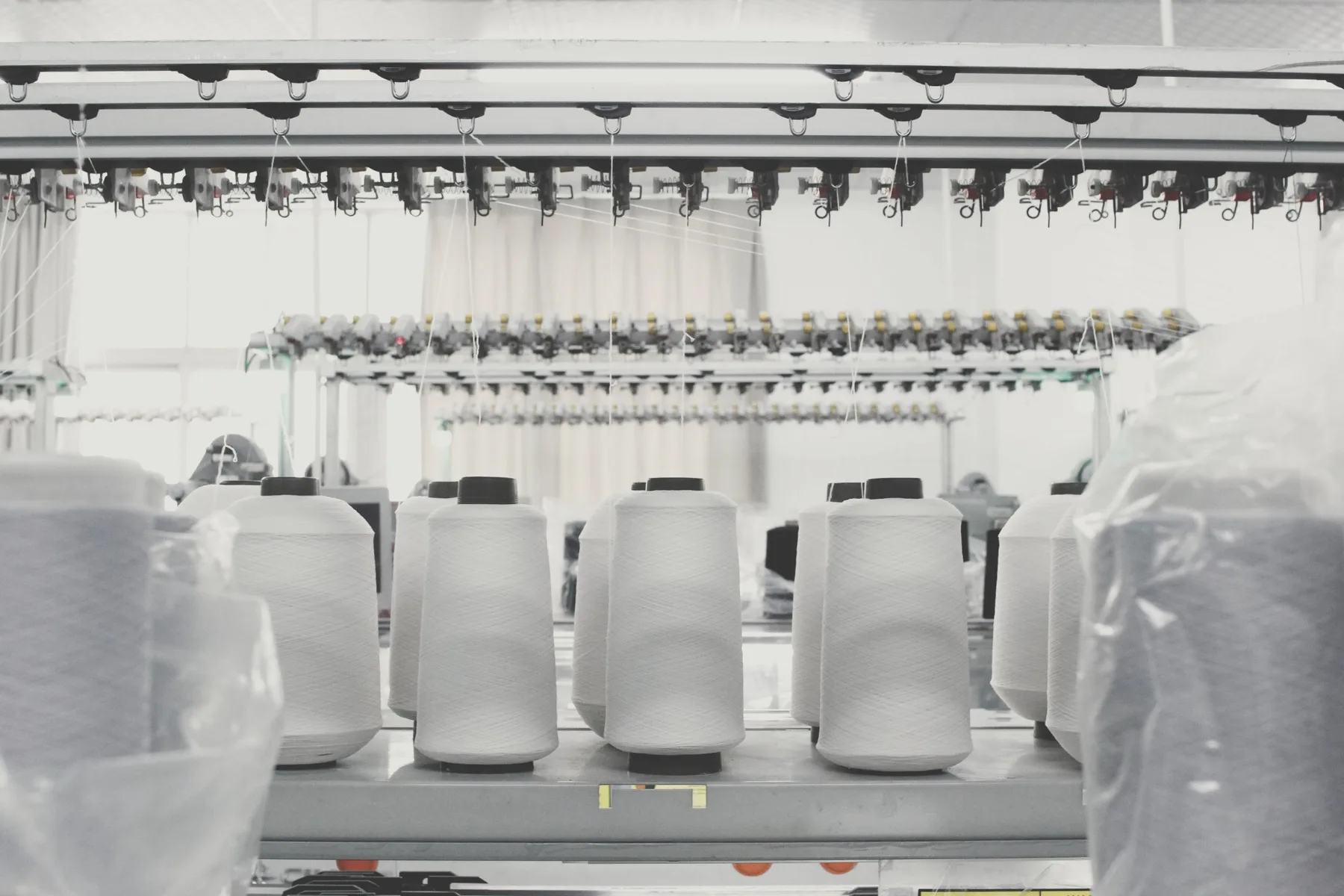 Cones of white yarn loaded on a knitting machine in a factory