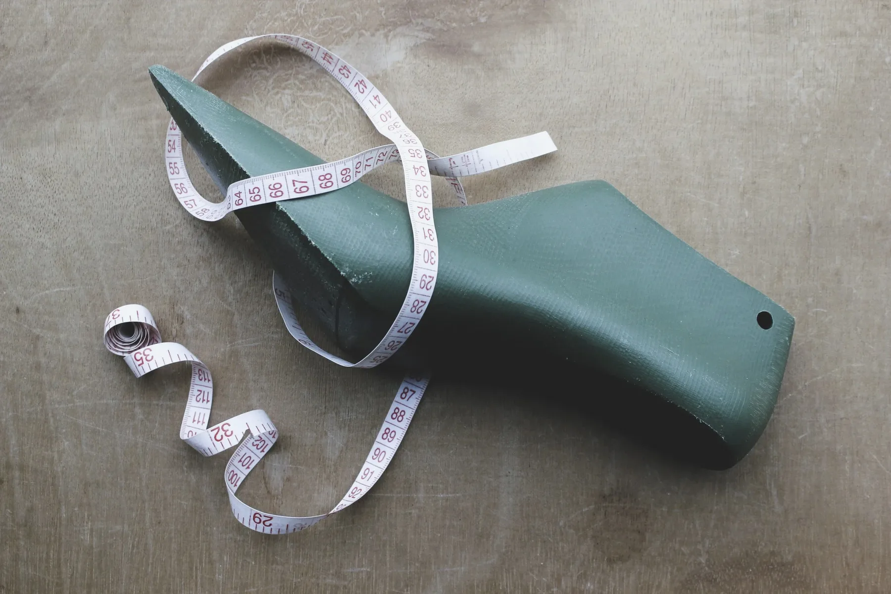 A green stiletto shoe last wrapped in a tailor's measuring tape